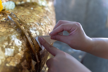 People cover the Buddha statues with a thin golden leaf