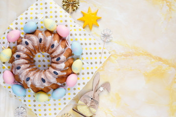 Big plate with cake and hand painted colorful eggs, on towel on yellow marble background. Close up. Decoration for Easter, festive background.Happy Easter!