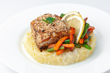 Fried perch fillet with rice and vegetables. On a white plate. On a white background. Isolated Close-up.