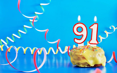 Birthday of ninety one years. Cupcake with white burning candle in the form of number 91. Vivid...