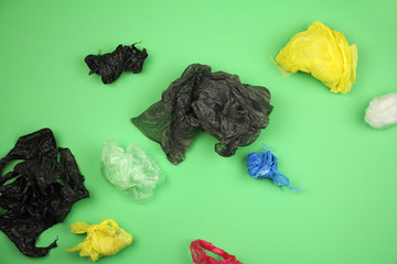 lot of crumpled used plastic bags different color on green background, big ecological problem