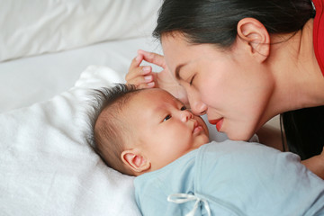 Obraz na płótnie Canvas Close up mother kissing newborn baby boy lying on the bed.
