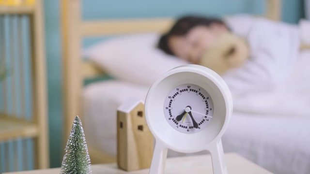 Child girl sleeping with alarm clock on the wooden bed in her bedroom, Happy asian child little girl and alarm clock wake up on the morning