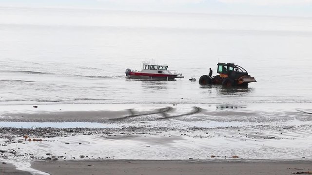 Recovery of a fishing charter boat in Cooks Inlet with log skidder at Anchor Point beach in Alaska