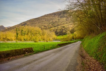 un camino rural corre bordeando un rio en un paisaje de montañas