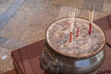 Fototapeta na wymiar A bowl of lit burning incense at a Buddhist temple in Bangkok, Thailand.