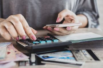 woman hand calculating her expenses and debt from credit cards with smart phone 