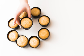 cupcakes without cream on a white background with a place for the text. The girl takes a cupcake from a pile of sweets. copyspace