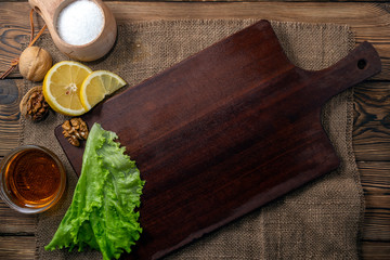Cutting board on a wooden table. With spices, herbs, butter and lemon for cooking. Copy space top view.