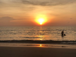 the sun sets on the horizon where the sea joins the sky. people-adult and child-swim in the sea and enjoy the Golden sunset on the beach