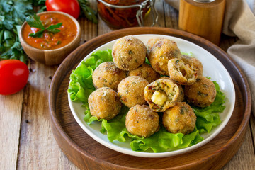 Arancini. Italian Rice Balls with Mozzarella and Sun-dried tomatoes, with tomato sauce on wooden table.
