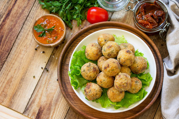 Arancini. Italian Rice Balls with Mozzarella and Sun-dried tomatoes, with tomato sauce on wooden table. Top view flat lay background. Copy space.