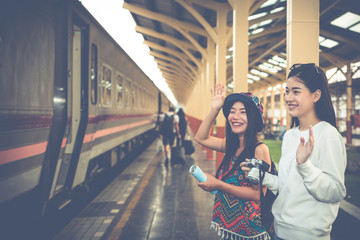 Two women are happy while traveling at the train station. Tourism concept