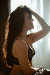 Obraz na płótnie Canvas young pretty woman in black bra sitting on bed. morning time