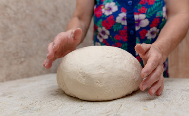 Woman kneads dough with hands in the kitchen