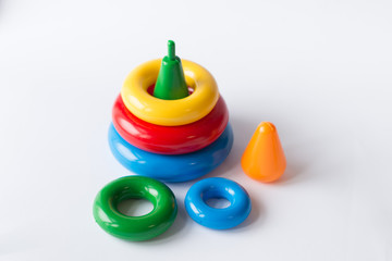 Pyramid build from colored rings with a clown head on top. Toy for babies and toddlers to joyfully learn mechanical skills and colors. Studio shot on white background.