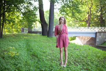 Cute and beautiful blond girl posing for photo in dress at the park