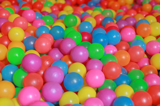 Many colorful plastic balls in a kids' ball pit at a playground.