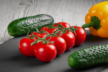 Tomatoes on a slate among other vegetables.