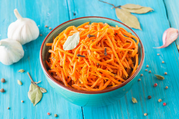 Appetizer of carrots in Korean in a ceramic plate on a blue background