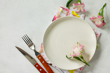 Spring or Mother's Day table setting. Plate, cutlery and napkin on white stone table. Top view flat lay background with copy space.
