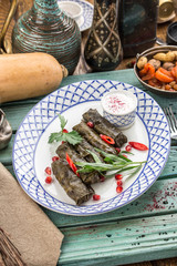Fototapeta na wymiar Dolma stuffed grape leaves with rice and meat on blue wooden table