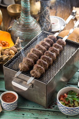 smoking lamb kebab on skewers served on the grill on blue wooden table