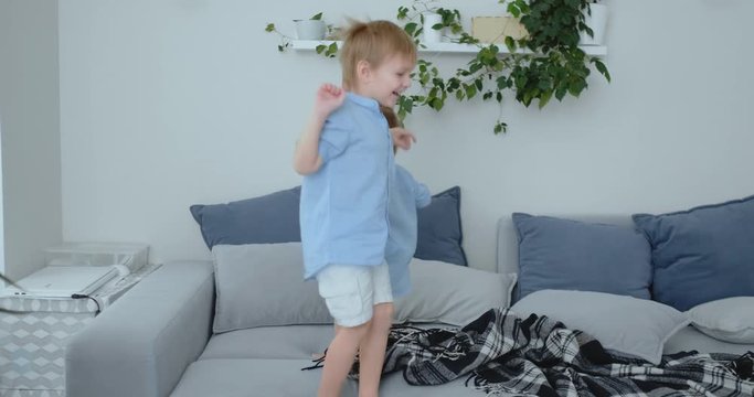 Two little boys jumping on the couch and having fun