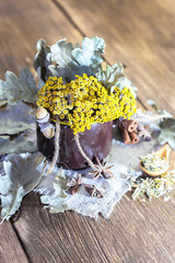 Herbal medicine, homeopathy, the collection of medicinal herbs for tea and medicines. Dried tansy flowers and oak leaves in a cup on the background of a wooden table in a rustic style