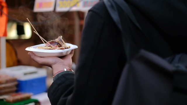 Man serving fresh grilled squid after buying food