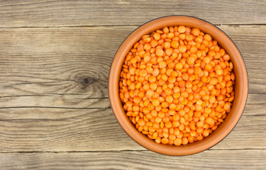 Red lentils in plate on wooden background