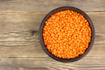 Red lentils in plate on wooden background
