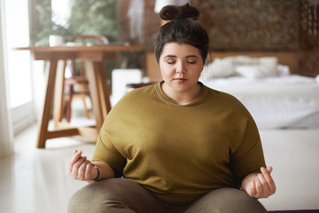 Young woman meditating at home, make mudra gesture