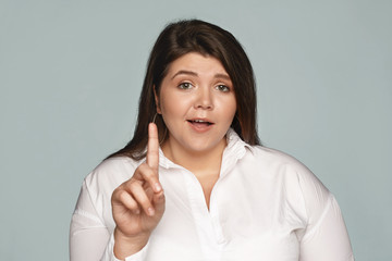 Wait a minute! Emotional indignant young plus size female saying No, showing fore finger,...