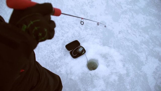 angler catches pike perch in the dark with a winter sounder