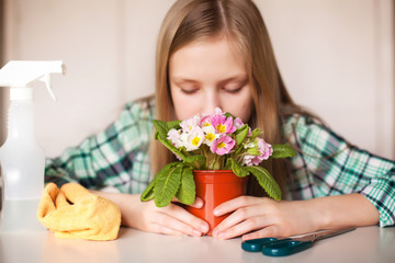 A girl sniffs a flower and cares for plants in her home, close-up