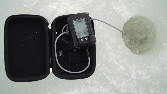 fisherman catches fish with a winter echo sounder in a hole in a river