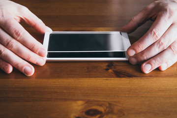 Man hands fingers hold smartphone screen protective covering glass on top of smartphone, about to install the protection glass. Protecting from scattering, scratches and cracks concept.