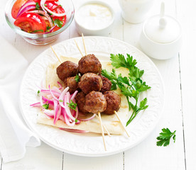 Lamb kebabs on skewers with onion and buttermilk sauce.