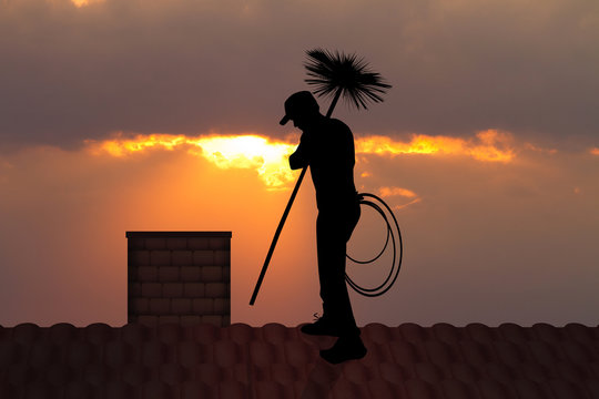 chimney sweep on roof at sunset