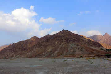Naklejka na ściany i meble Geological landscape of hatta dam characterised by dry and rocky mountains and lake between scenery mountains, water reservoir Between hills in Dubai, United Arab Emirates