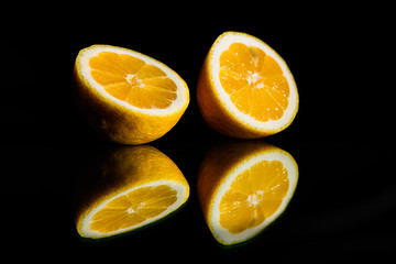 Naklejka na ściany i meble Lemon on a glass table, isolated on a black background, reflection of a lemon. additive for whiskey