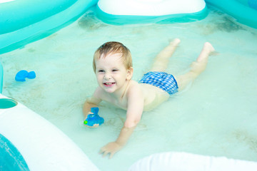 Fototapeta na wymiar Happy beautiful little boy bathes in pool
