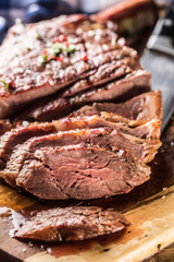 Freshly grilled tomahawk steak on slate plate with salt pepper rosemary and parsley herbs. Sliced pieces of juicy beef steak