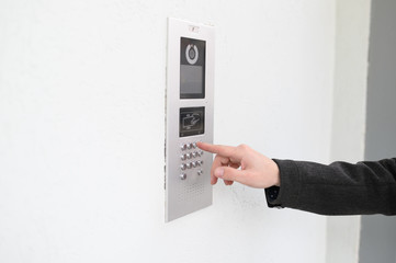 Close-up of intercome keyboard of residential building with finger entering code