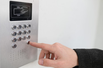 Close-up of intercome keyboard of residential building with finger entering code