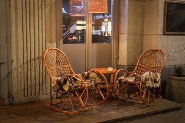 Rustic Sidewalk Cafe with Wooden Tables, Flower Pot and Plaids on Wicker Chair Outdoors
