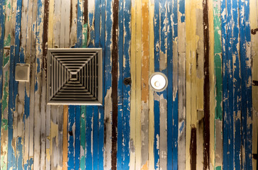 Fototapeta na wymiar Air conditioner mask and lighting On the ceiling that decorated with old wooden panels and peeling paint