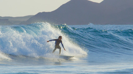Pro surfboarder riding big barrel ocean waves in beautiful Fuerteventura.