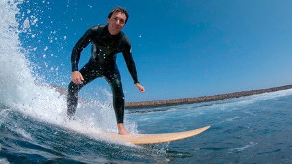 CLOSE UP: Stoked surfboarder smiling and riding a wave to the coast in Spain.